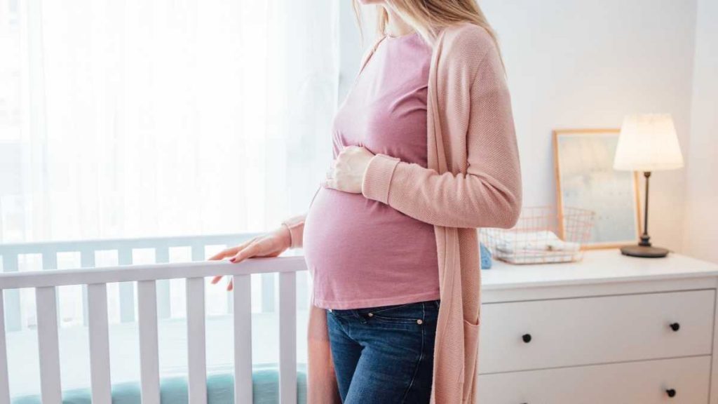 pregnant mom standing near crib ready for baby