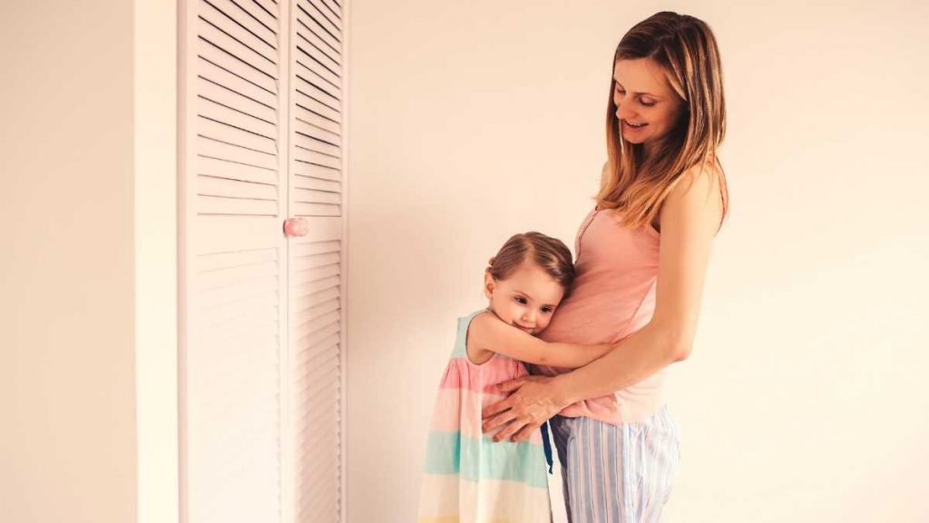 toddler cuddling moms pregnant belly