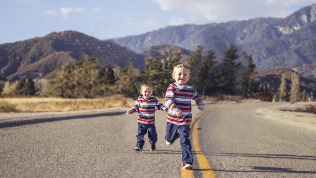 2 toddler boys running on a road