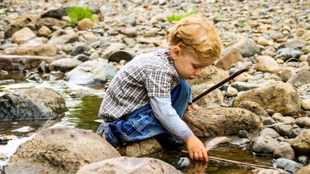 child learning in nature on stony beach