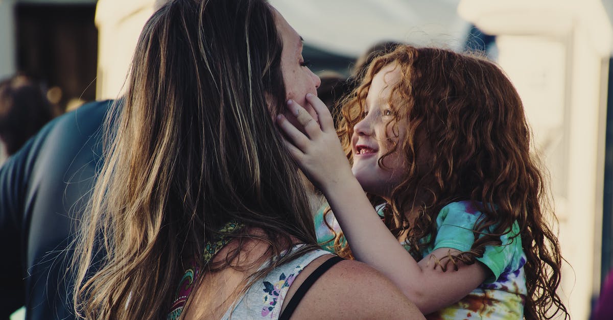 woman-carrying-girl-while-showing-smile